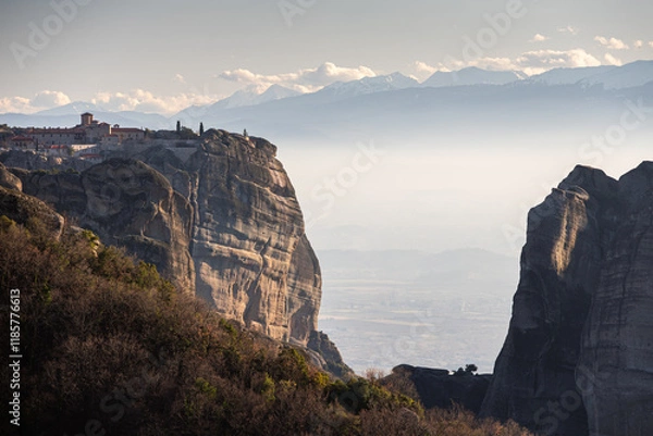 Fototapeta Travel to Meteora. The Monastery of Holy Trinity photographed in amazing sunset light with mountains in foreground. Travel to Orthodox iconic place of Meteora in Greece.