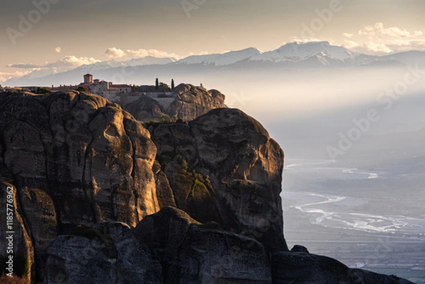 Fototapeta Travel to Meteora. The Monastery of Holy Trinity photographed in amazing sunset light with mountains in foreground. Travel to Orthodox iconic place of Meteora in Greece.