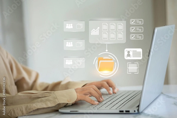 Obraz A person is typing on a laptop with a screen showing a file folder. The folder is labeled Work and has a yellow icon