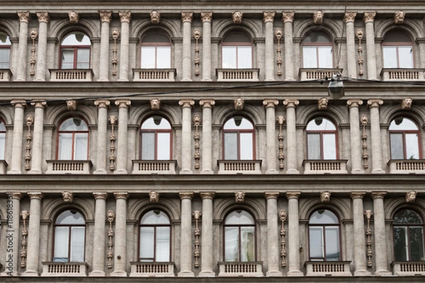 Fototapeta Detail of the facade of a multistory building in classical style with columns and windows.