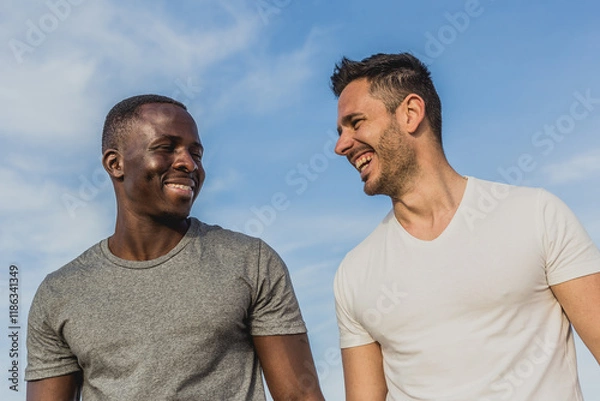 Fototapeta One Caucasian and one Black man laughing together on the beach after exercising