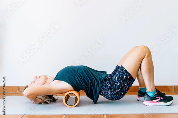 Obraz Runner practicing back self-massage with foam roller post-workout