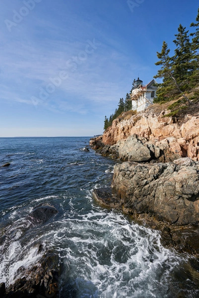 Fototapeta A beautiful clear day with a blue sky at Bar Harbor lighthouse in Acadia National Park. The lighthouse stands above a steep rocky cliff.