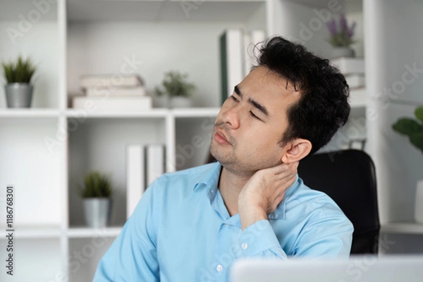 Fototapeta Young Businessman Experiencing Discomfort at Work in Modern Office Setting