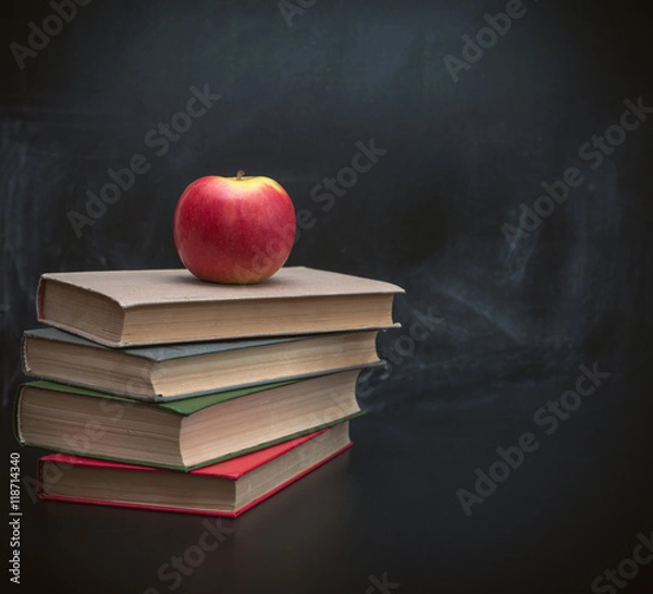 Fototapeta Стопка книг и красное яблоко на фоне черной школьной доски для мела 