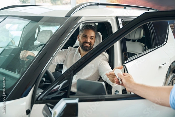 Fototapeta Happy young man receiving car key from salesman