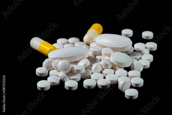 Obraz White round tablets are scattered on a black background.