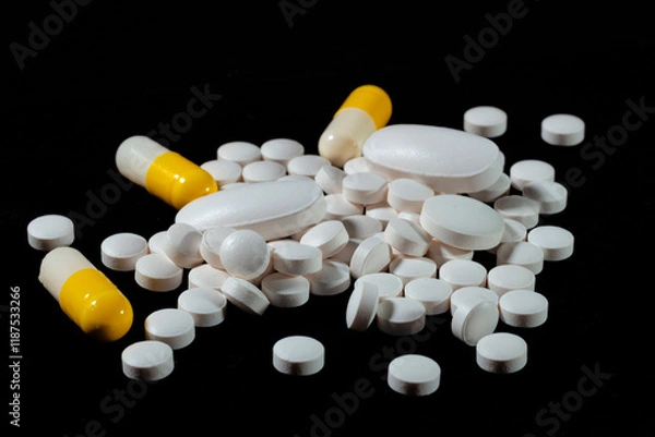 Obraz White round tablets are scattered on a black background.