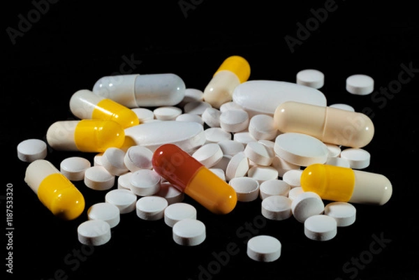Fototapeta White round tablets are scattered on a black background.