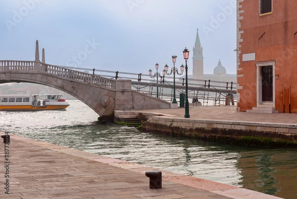 Fototapeta Beautiful marble bridge over a canal with historical architecture in the background, Venice, Italy