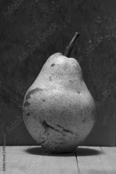 Obraz A pear placed on wooden desk with dark teftured background.