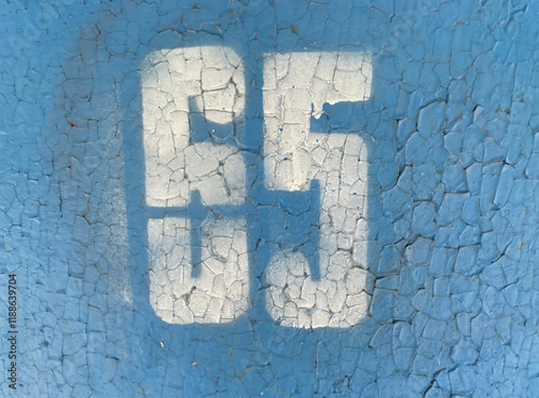 Fototapeta White number 65 on textured background with old cracked blue paint. Sixty-five