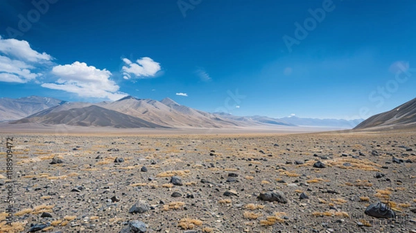 Fototapeta A high-altitude desert with colorful striated rock formations under a vast, clear sky.