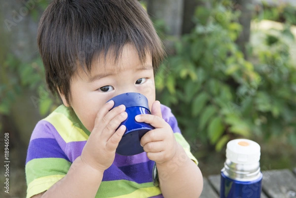 Fototapeta 公園で水筒のお茶を飲む男の子
