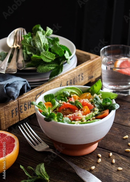 Fototapeta Quinoa salad with tomatoes, avocado, grapefruit, pine nuts and mint served in a bowl