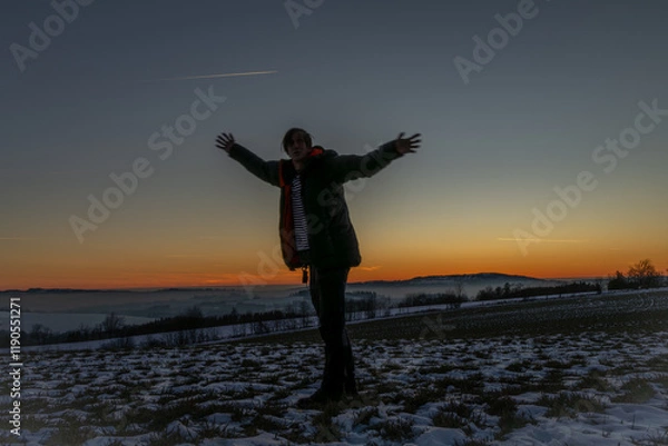Fototapeta Winter frosty view for sunset over snowy field with silhouette of man