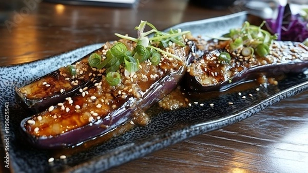 Fototapeta Grilled eggplant halves glazed with sweet miso sauce, topped with toasted sesame seeds and scallions, served on a Japanese style rectangular black plate