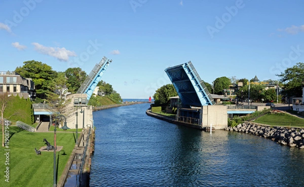 Fototapeta US 31 Island Lake Outlet Bridge, znany również jako most Pine River Channel, z czerwoną latarnią morską przy wejściu do portu w Charlevoix w stanie Michigan z jeziora Michigan.