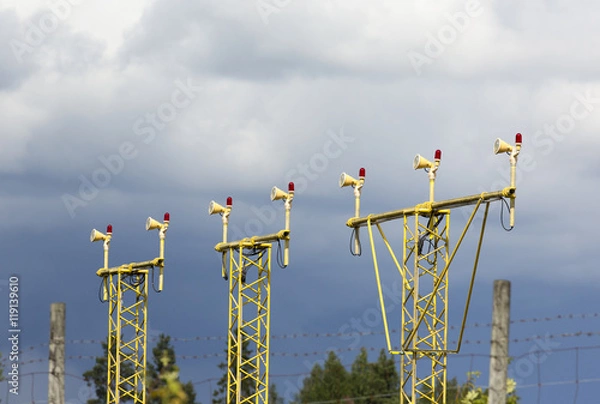Fototapeta Airport landing lights against a dramatic sky with clouds.