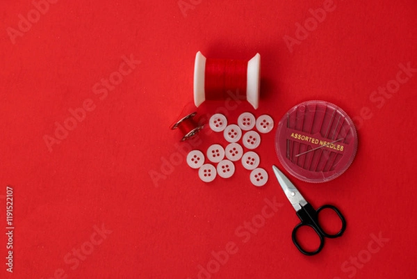 Fototapeta Sewing kit: thread, buttons, needles, scissors on red background.