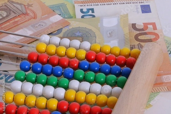 Obraz close up of a slide rule with colorful wooden balls lies on a stack of euro bills