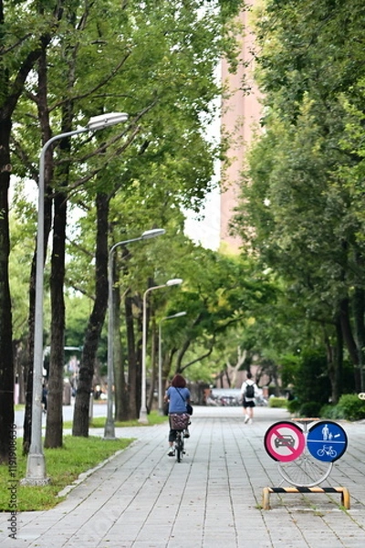 Fototapeta This photo showcases NTU’s thoughtful pathway design with clearly marked pedestrian and bike lanes. By prohibiting cars, NTU creates a peaceful and green campus that prioritizes safety and environment