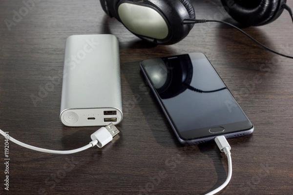 Fototapeta mobile phone and power bank battery on dark background