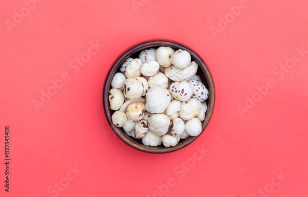 Obraz Top View of Makhana or Fox Nut in a Wooden Bowl Isolated on Red Background with Copy Space, Also Known as Lotus Seed Pop, Euryale Ferox or Gorgon Nut