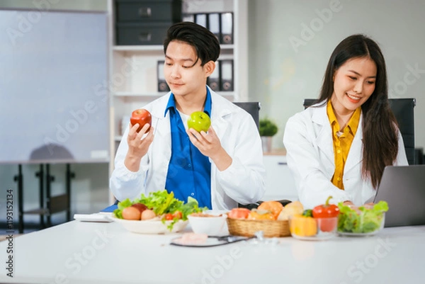 Obraz Two nutritionists,female and male, work in a hospital, analyzing vegetable and fruit salads, offering online advice, helping patients embrace clean eating habits and weight control for better health