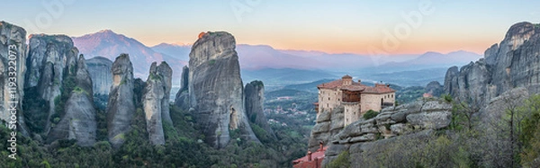 Fototapeta Sunset view of the Meteora monasteries in Greece, perched on towering rock formations, surrounded by a stunning mountainous landscape.