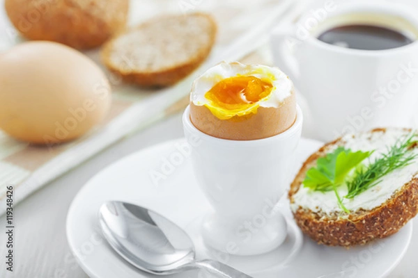 Obraz Healthy breakfast with perfect soft boiled egg, bread and butter, coffee cup. Delicious homemade food.