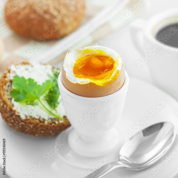 Obraz Perfect soft boiled egg, open bread sandwich with butter and cup of coffee on a table. Traditional food for healthy breakfast.