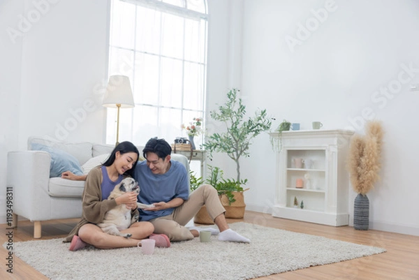 Fototapeta Asian couple spends quality time with their pug dog in their living room