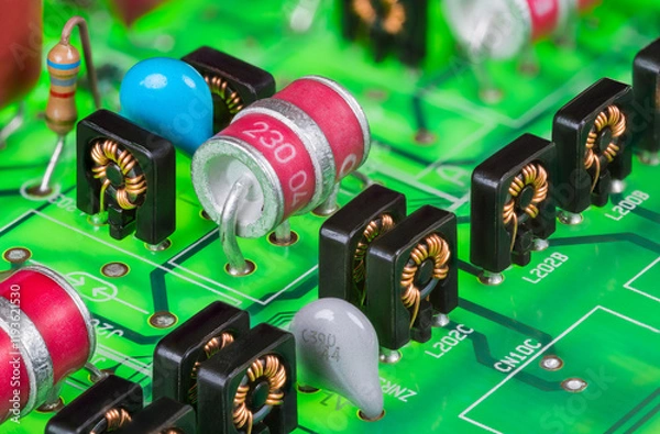 Fototapeta Red electrode gas discharge surge arresters and toroid inductors in black case. Closeup of electronic components on green printed circuit board in digital telephone switch analog part line protection.