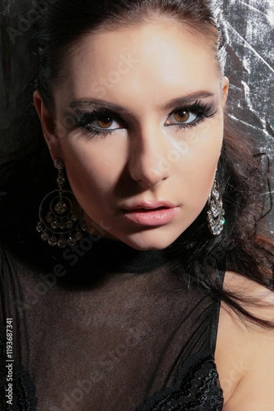 Fototapeta a beautiful, fashionable young brunette of tall stature, on a white background in latex gloves and a black bodysuit, stands in the studio