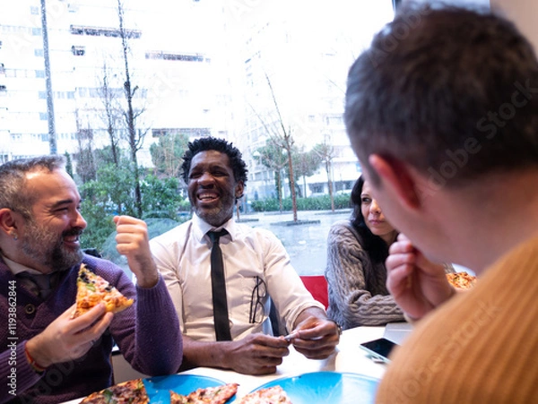 Fototapeta Seen from the perspective of a fourth person in a beige sweater, three colleagues enjoy pizza and laugh together, with a phone on the table. The woman appears slightly more serious