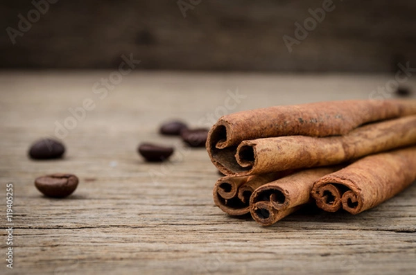 Obraz Cinnamon sticks and coffee grains on old rustic background, seasoning ingredients for cooking or baking.