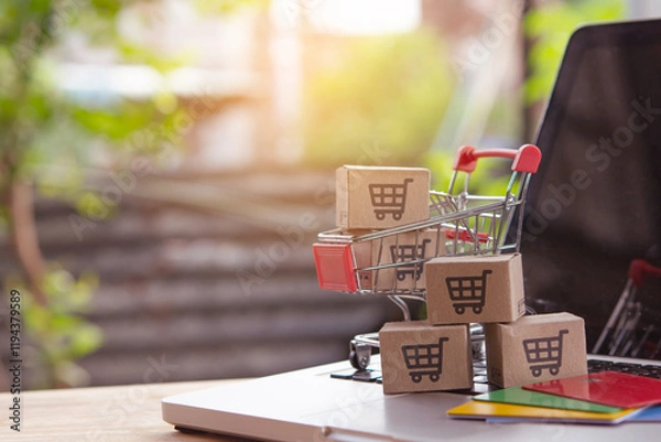 Fototapeta Shopping online. Credit card and cardboard box with a shopping cart logo in a trolley on laptop keyboard. Shopping service on The online web. offers home delivery