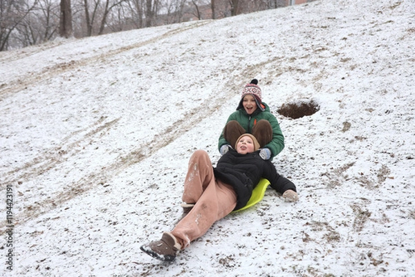 Fototapeta Children are walking, hiking,, sledding and playing in a snowy park. Winter fun and outdoor activities with kids