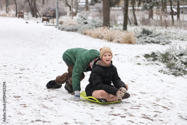 Fototapeta Children are walking, hiking,, sledding and playing in a snowy park. Winter fun and outdoor activities with kids
