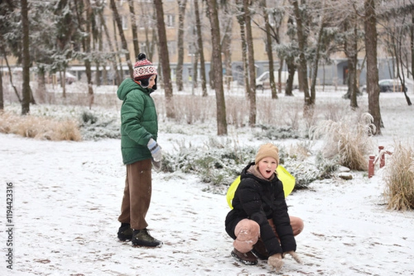 Fototapeta Children are walking, hiking,, sledding and playing in a snowy park. Winter fun and outdoor activities with kids