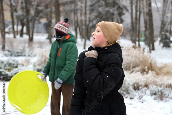Fototapeta Children are walking, hiking,, sledding and playing in a snowy park. Winter fun and outdoor activities with kids
