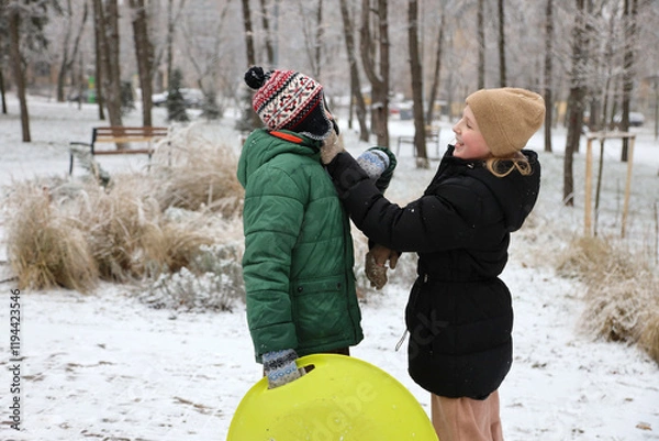 Fototapeta Children are walking, hiking,, sledding and playing in a snowy park. Winter fun and outdoor activities with kids