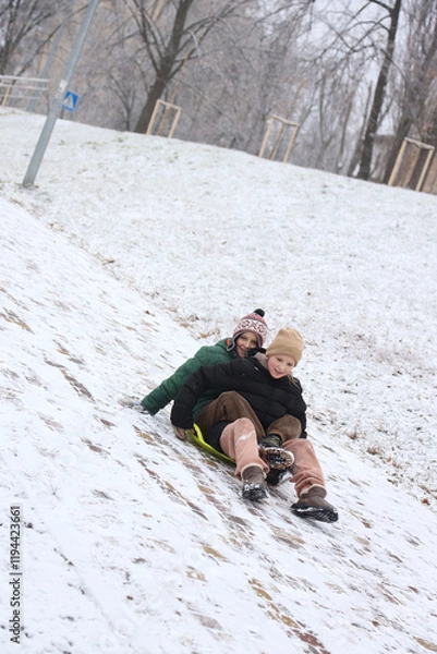 Fototapeta Children are walking, hiking,, sledding and playing in a snowy park. Winter fun and outdoor activities with kids