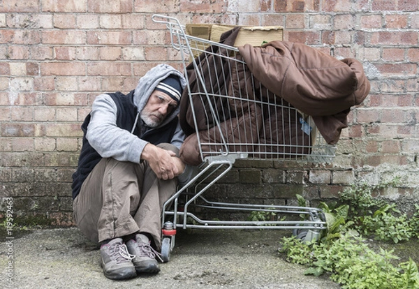 Fototapeta Homeless man out on the streets with his belongings in a trolley.