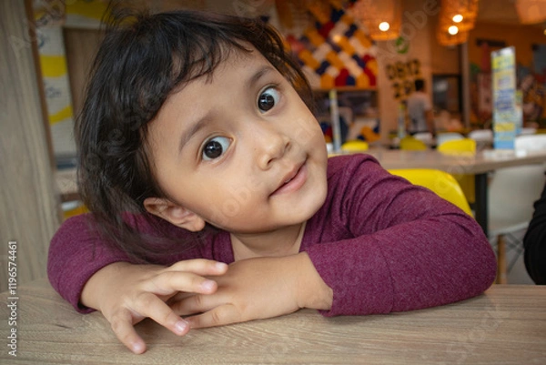 Fototapeta Smiling toddler girl with wide eyes open with folded hands