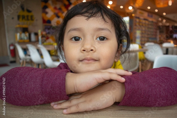 Fototapeta Smiling toddler girl with serious face resting on folded hands