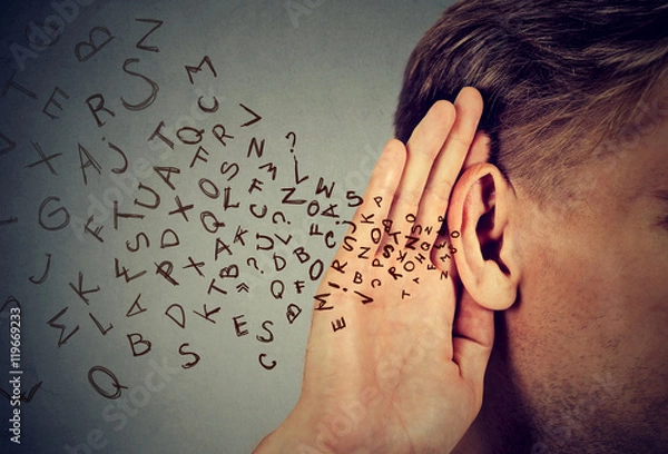 Obraz man holds hand near ear listens carefully alphabet letters flying in