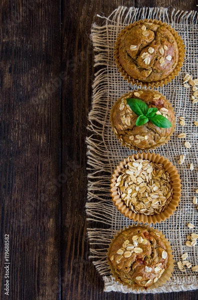Fototapeta Healthy zucchini and oatmeal muffins on a rustic background, overhead view