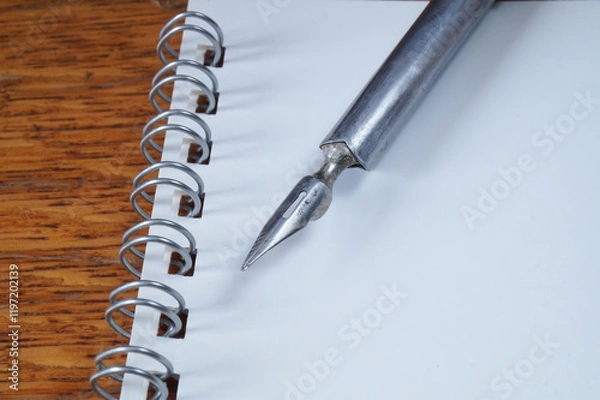 Fototapeta A fountain pen with a pen and a notebook on a wooden table